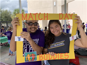 Picture of two Best Buddies students holding up a sign 